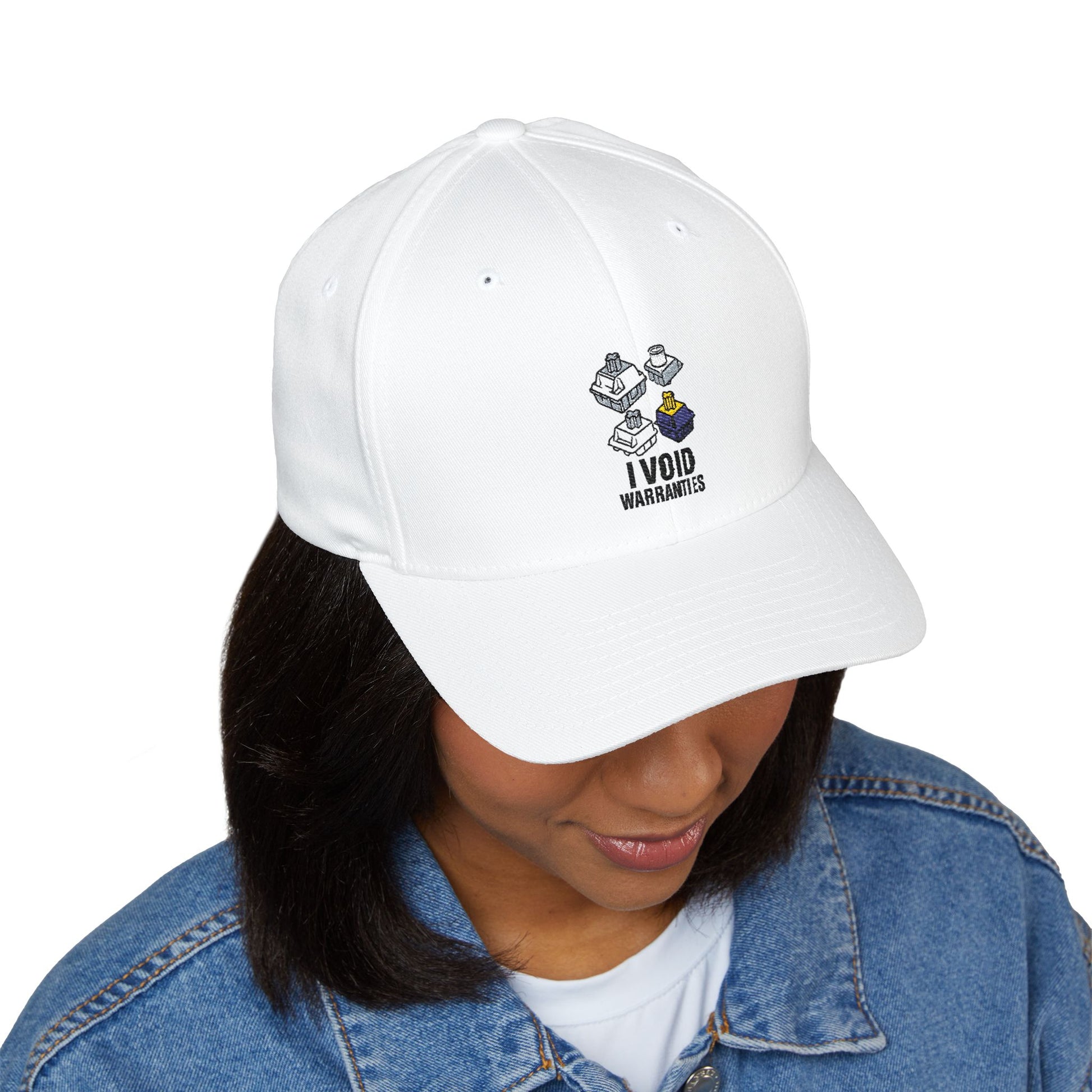 A woman wearing a white embroidered hat with a mechanical keyboard switch graphic and “I VOID WARRANTIES” design, styled with a denim jacket.